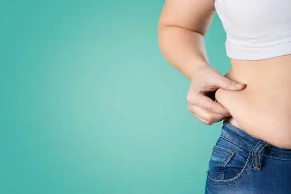 Image of woman pinching her love handles to show weight gain Pollokshields